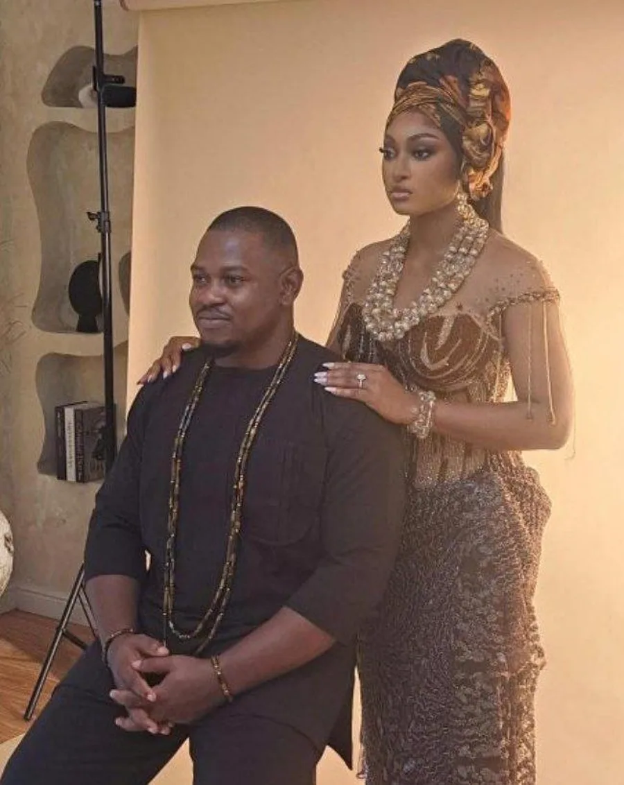 Kelvin seated with Ema standing beside him in traditional attire