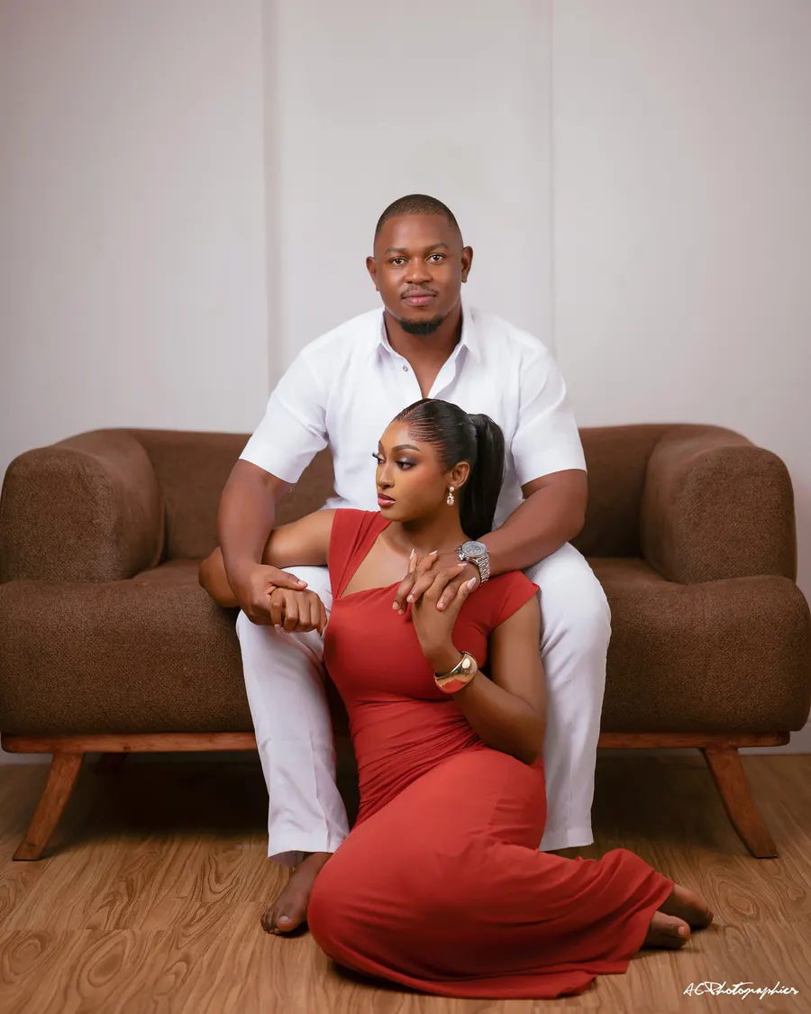 Emma in a red dress seated on the floor beside Kelvin